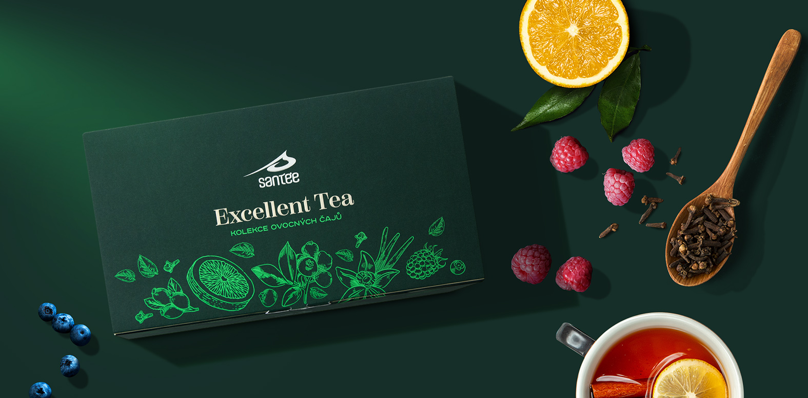 Dárková kolekce ovocných čajů Santée Excellent Tea na stole s ovocem a lžičkou má povedený návrh obalu
